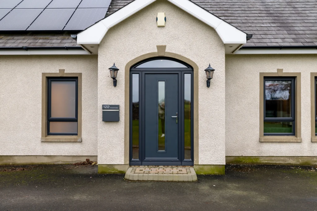 Anthracite grey composite front door with slim glazed panel in arched stone porch surround