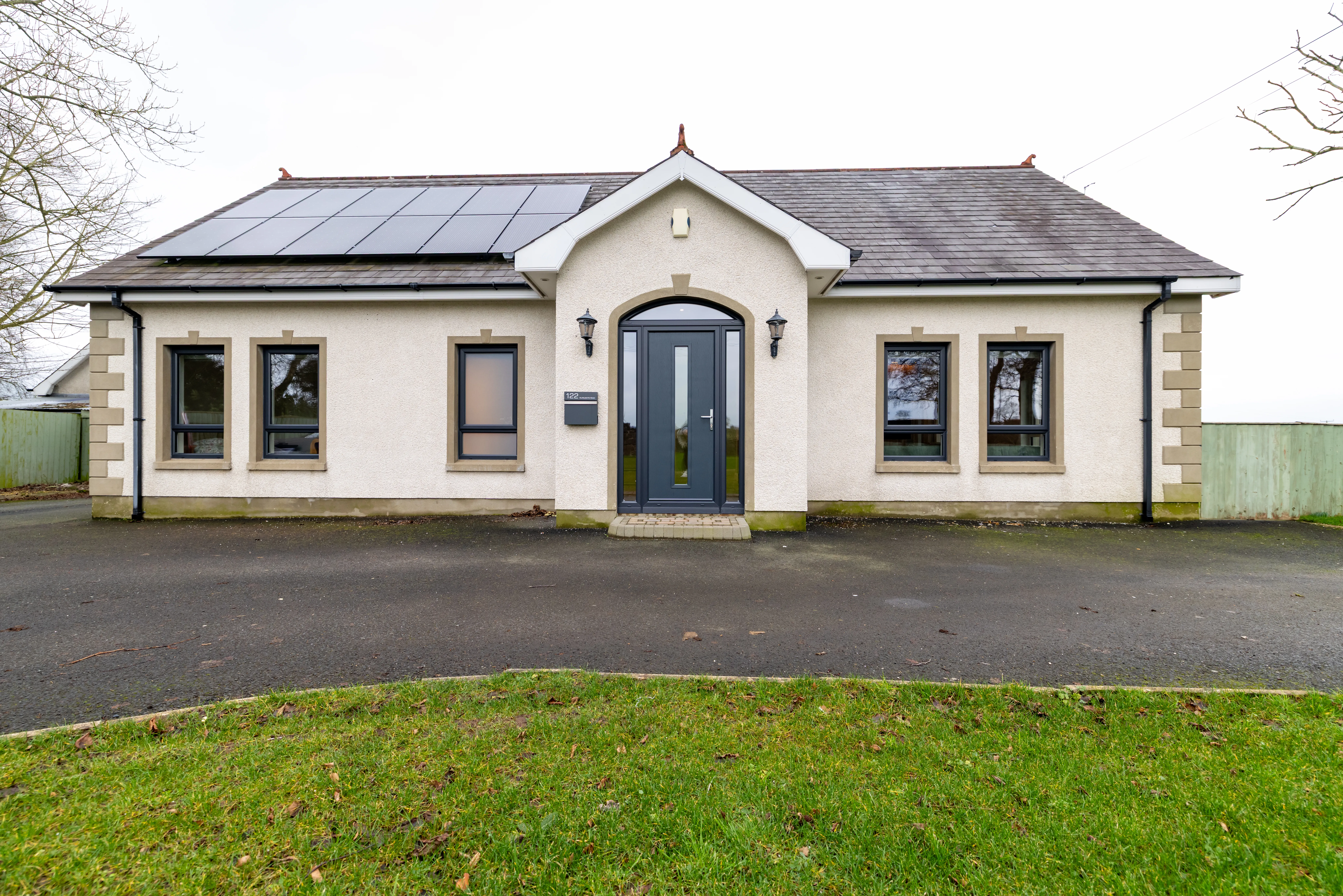 A full elevation of anthracite grey windows and a matching door fitted to a rendered building